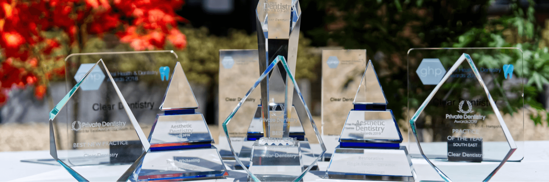 The practice's glass awards trophies lined up in front of the red acer outside the surgery
