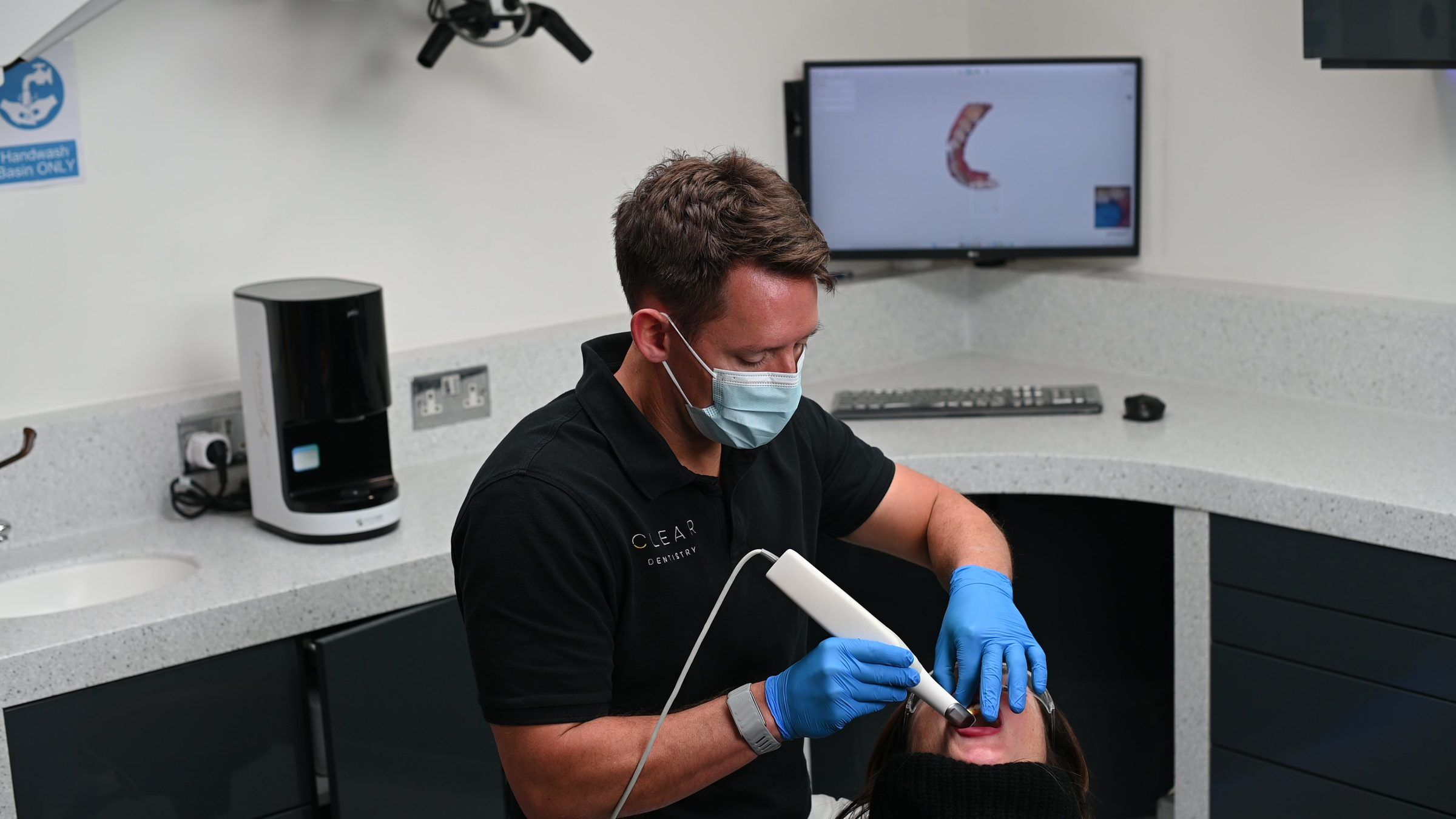 A dentist taking a digital scan, the 3D model building on screen