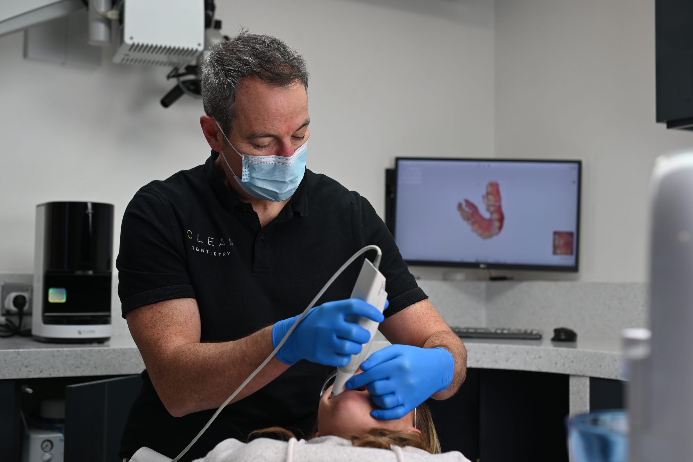 Dr Leigh Knowles taking a 3D iTero scan, with the patient's full arch building on the screen behind
